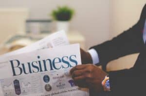 Business professional reading newspaper with market and economic news.
