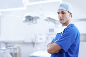 Surgical team member in scrubs and cap in a modern operating room.